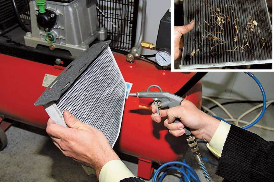 На фото мастер сервиса продувает радиатор кондиционера сжатым воздухом.