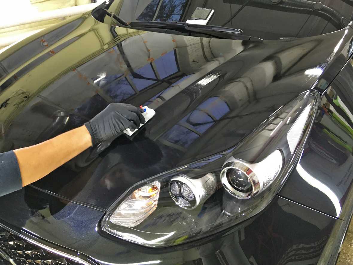 На фото мастер владимирского детейлинга «DT GARAGE 33» обрабатывает капот у KIA Sportage английской керамикой.