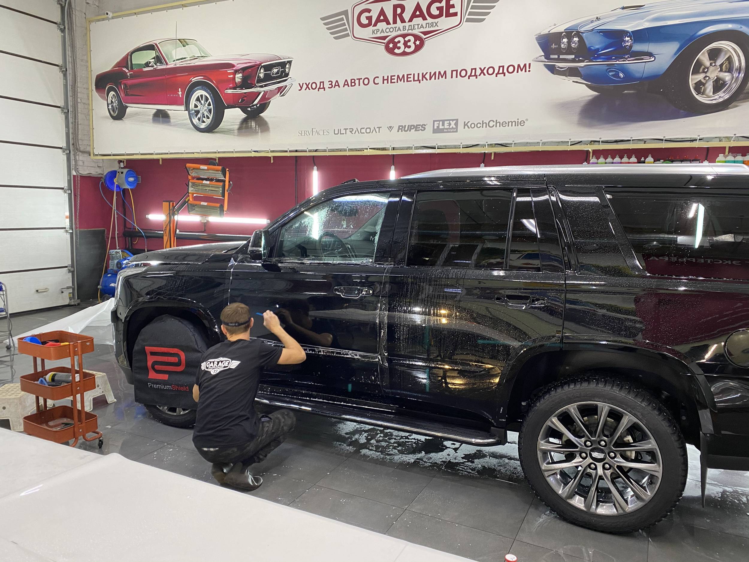 Смотреть на фото процесс оклейки водительской двери автомобиля Cadillac Escalade антигравийной пленкой.