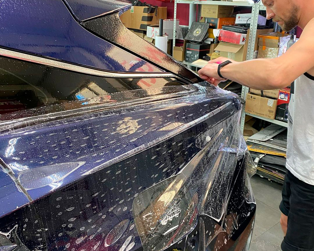 Смотреть на фото процесс оклейки антигравийной пленкой крыла автомобиля Lexus RX в детейлинге DT GARAGE 33.